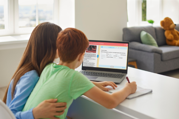 A parent and their child looking at a laptop with LiteracyPlanet on it.